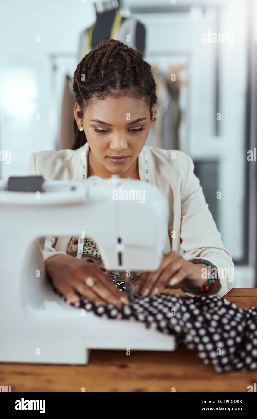 Putting her style into every stitch. a young fashion designer using a sewing machine in her workshop. Stock Photo