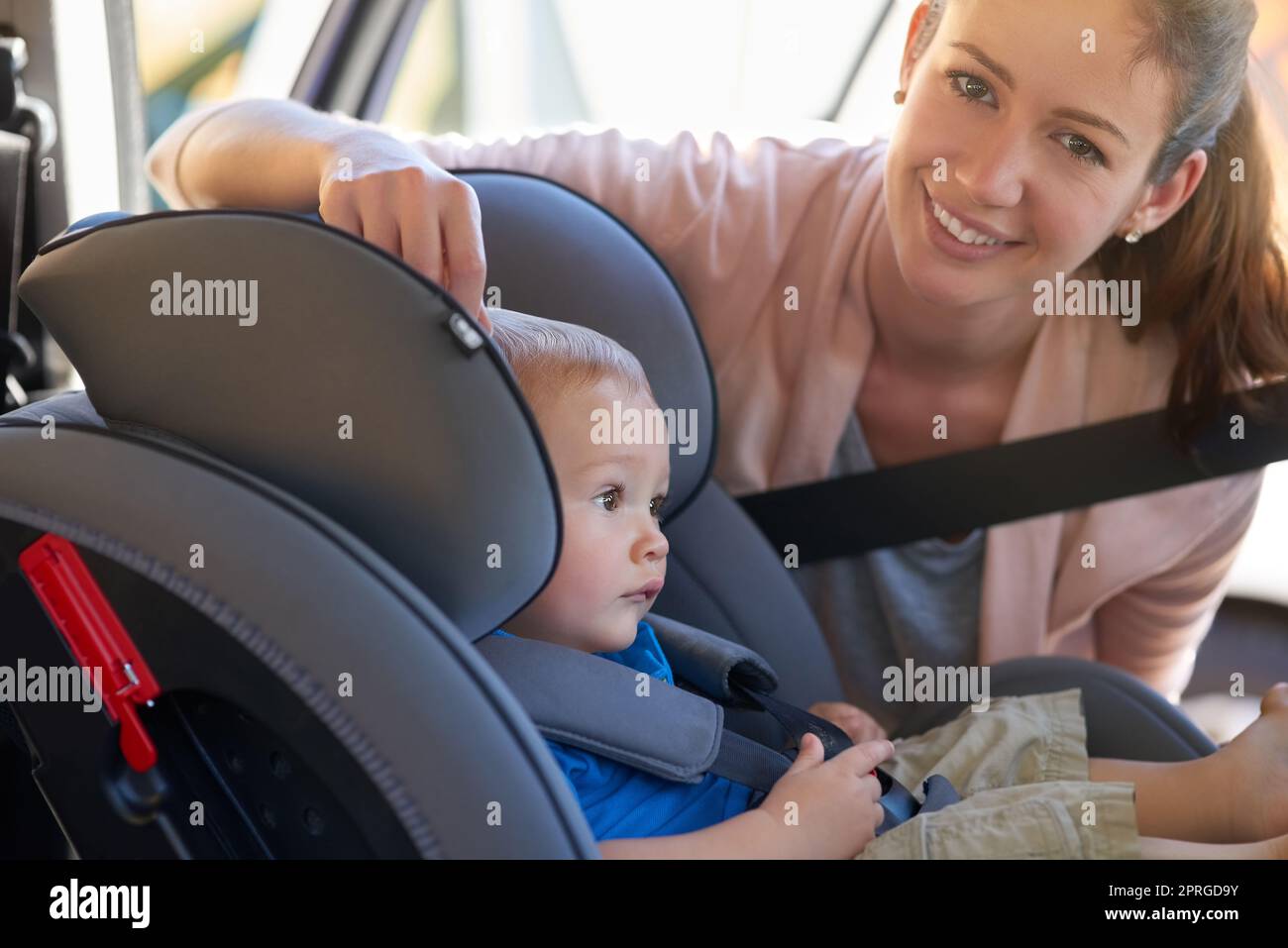 My childs safety is very important. Portrait of a mother fastening her baby boy safely in a car seat. Stock Photo