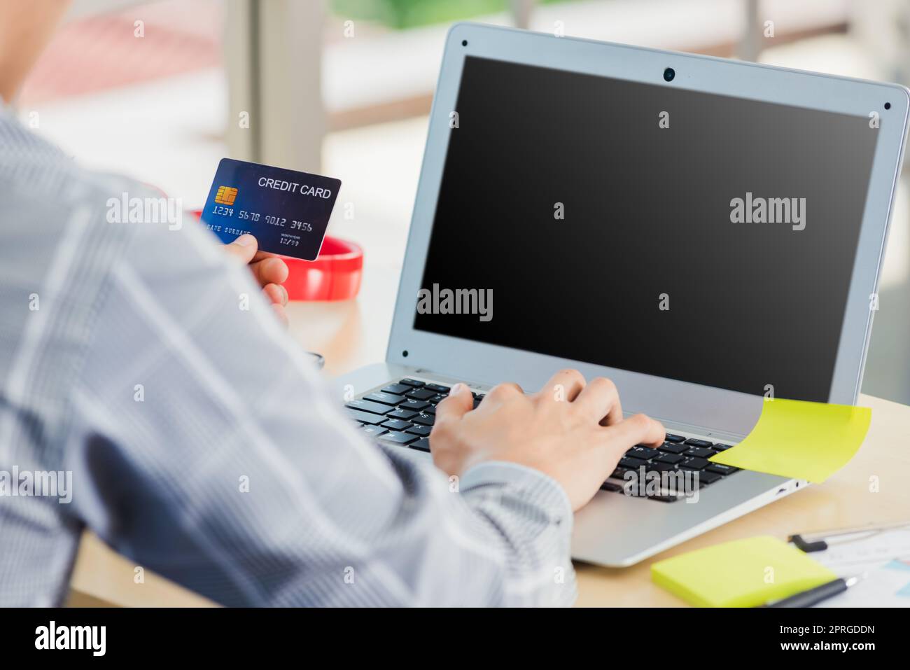 business man hand holding credit card and typing entering security code on a laptop computer Stock Photo