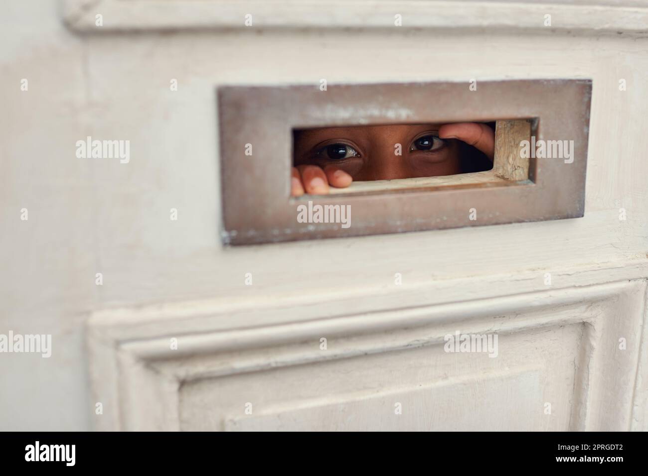 Peeking out the post box. a person looking through the opening of a letter box on a door. Stock Photo