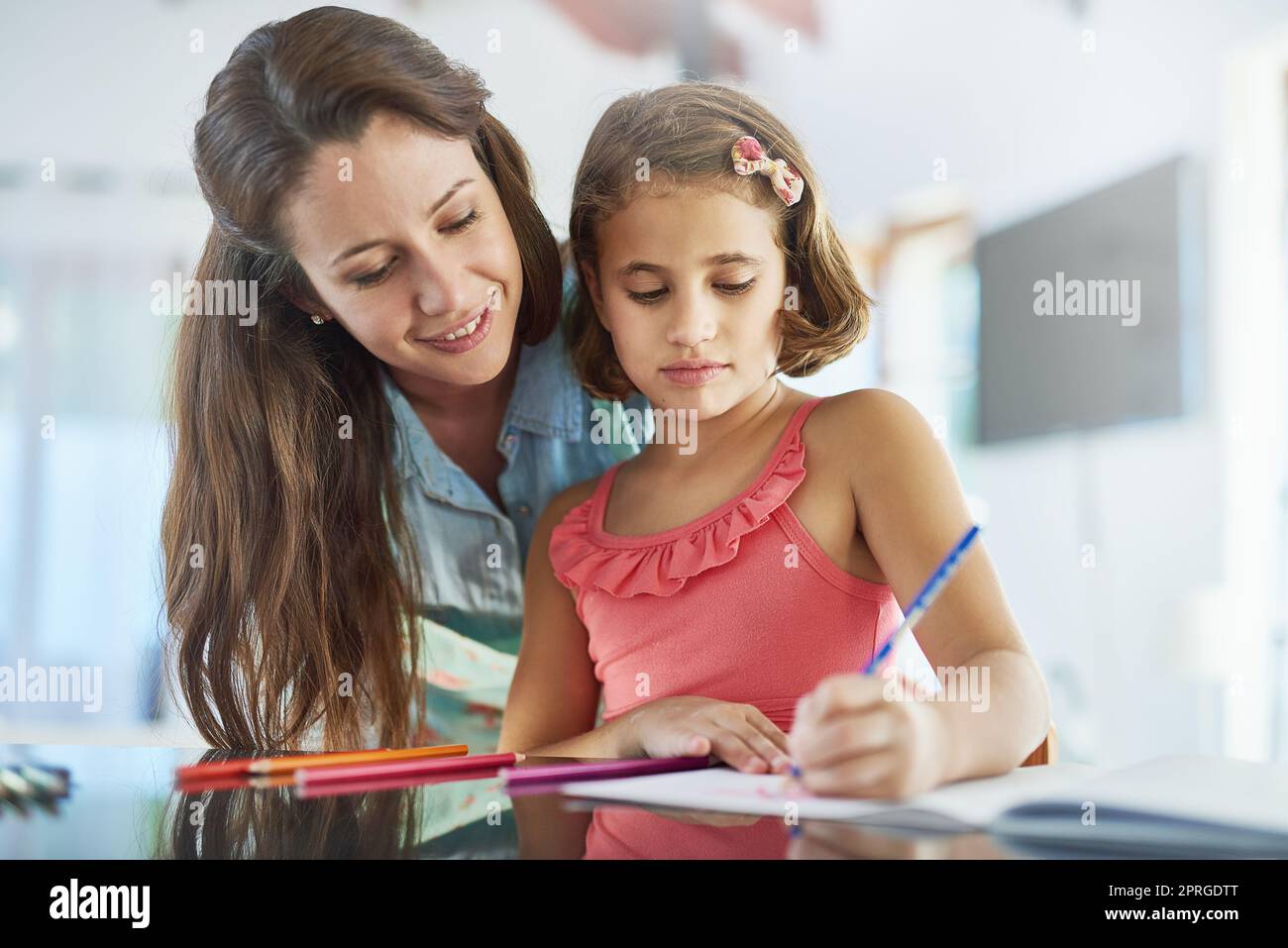 Watching her daughters creativity bloom. a mother watching her daughter colour in a picture. Stock Photo