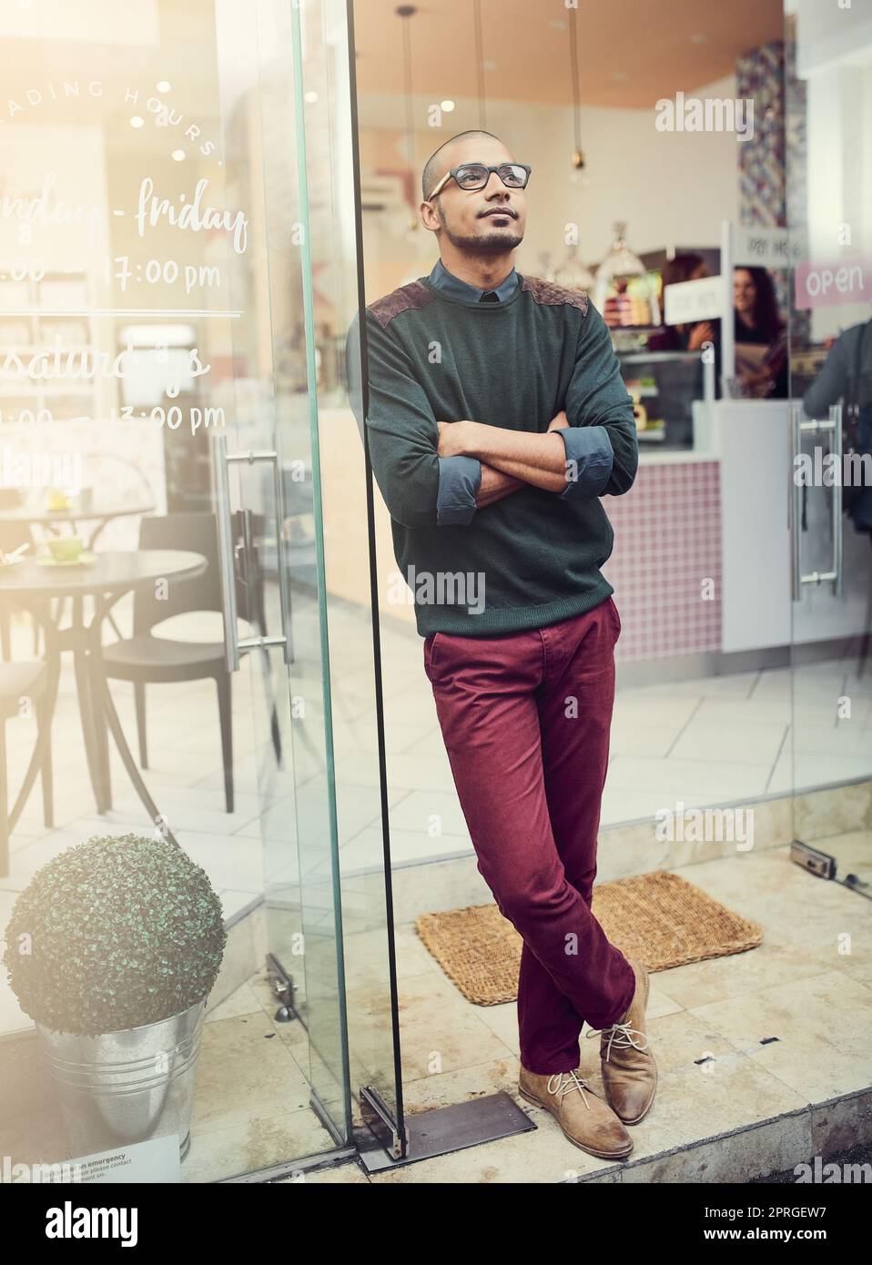 Achieving his goals. a young man standing in the entrance of a cafe. Stock Photo