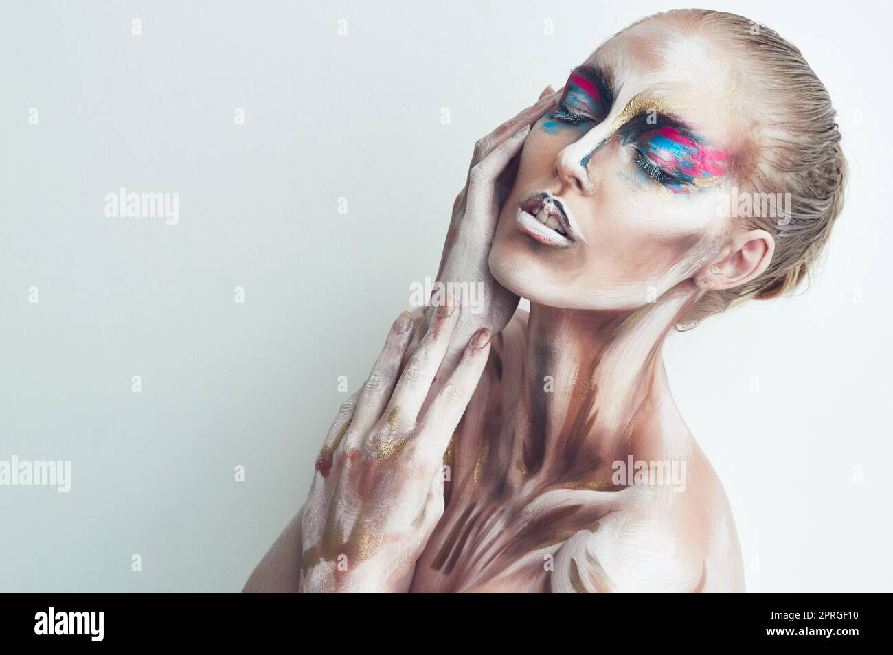 In full colour. Studio shot of a young woman posing with paint on her face. Stock Photo