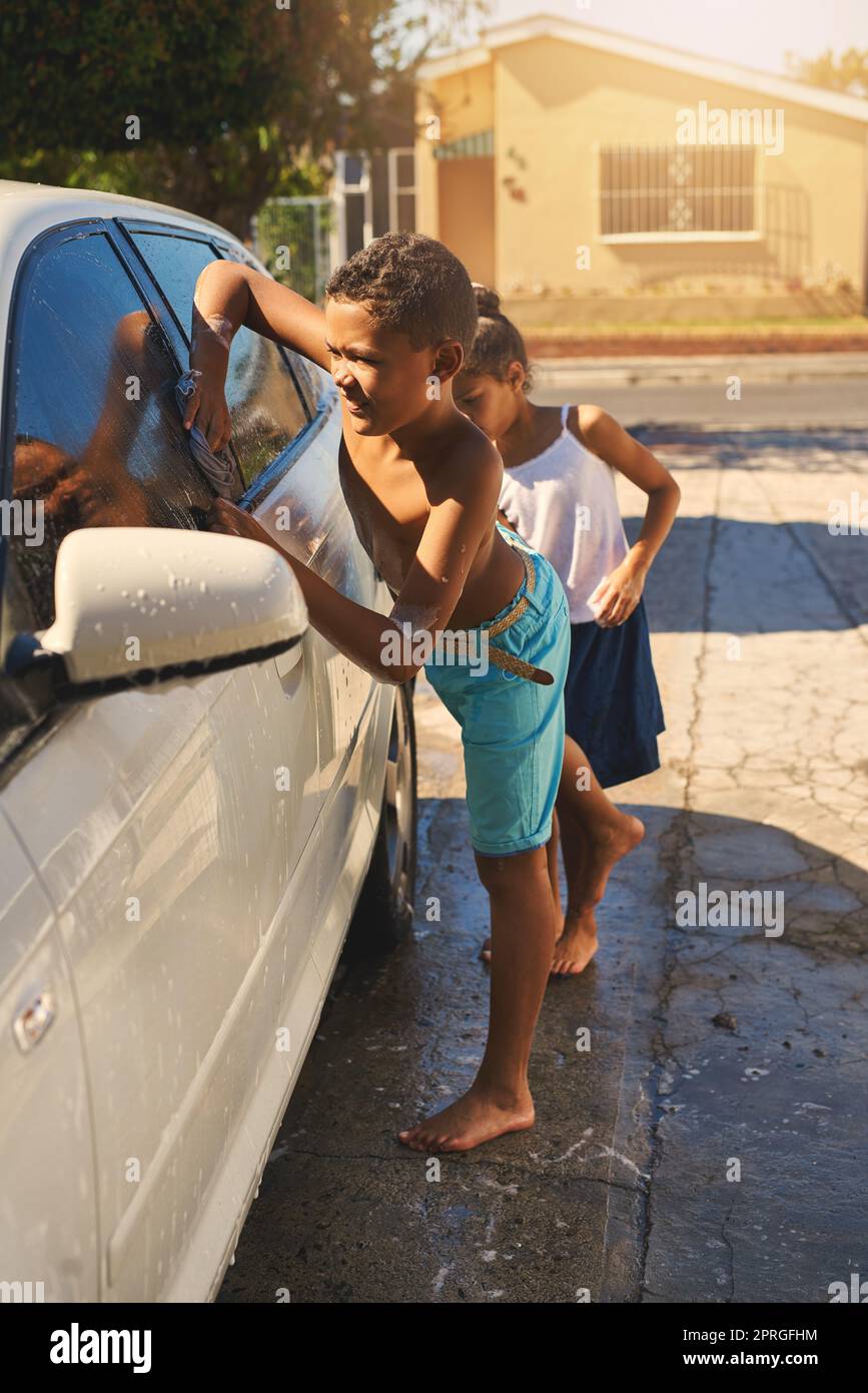 They enjoy lending a hand. a young boy and girl washing a car together outside. Stock Photo