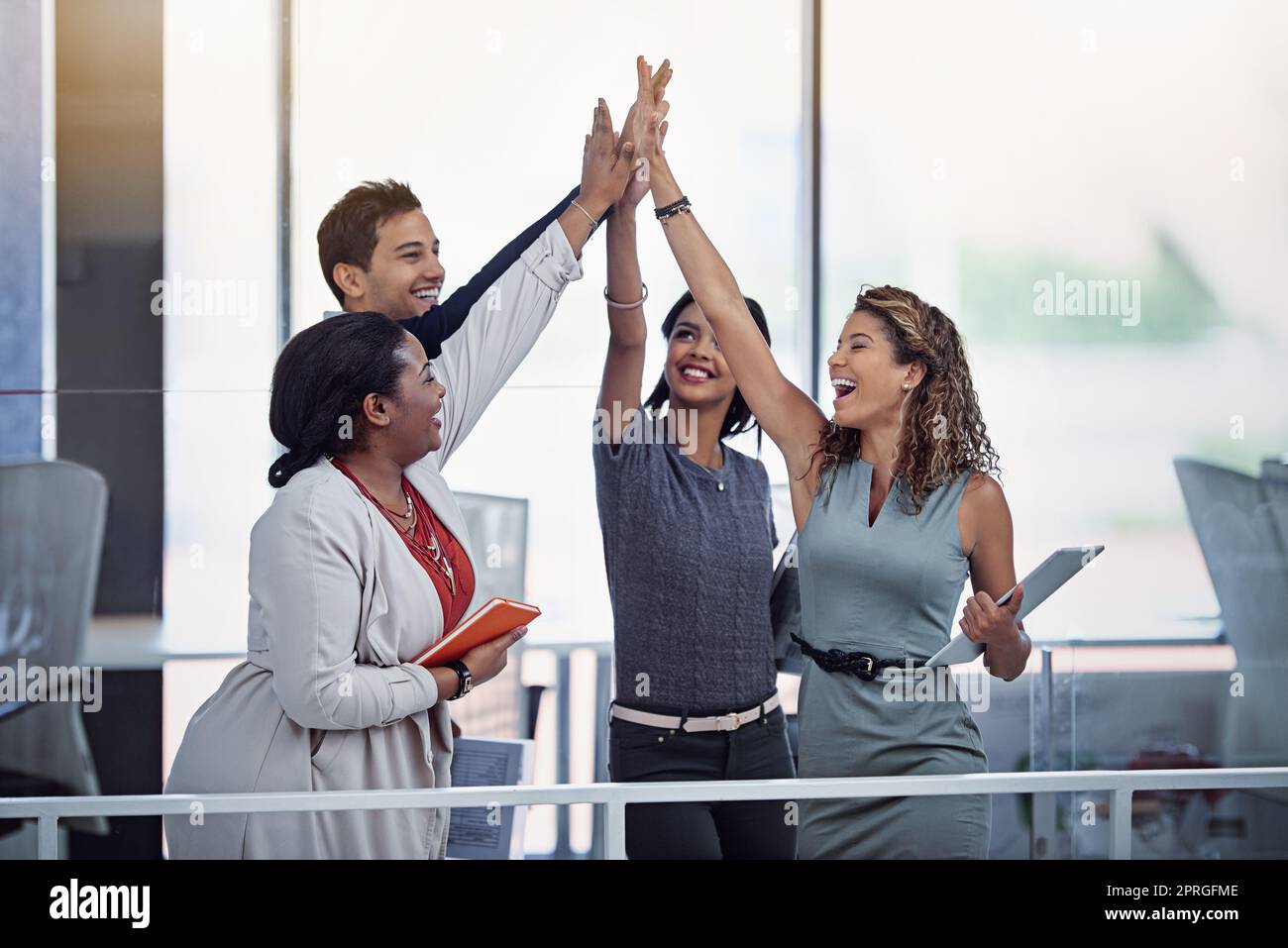 Teamwork makes the dream work. a group of colleagues high fiving together in an office. Stock Photo