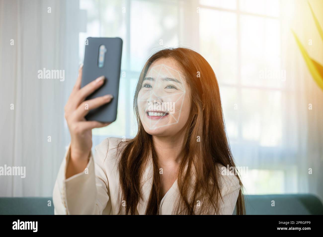 Asian women use smartphone for access control face recognition in private identification on sofa living room at home Stock Photo