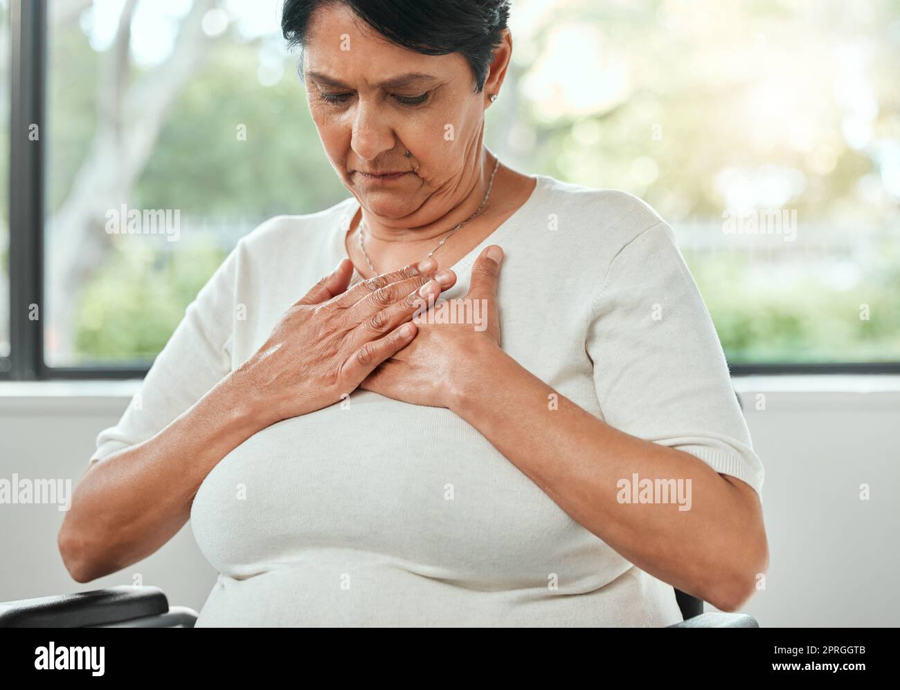 Why does my chest hurt like this. an unrecognizable woman experiencing chest pain while sitting