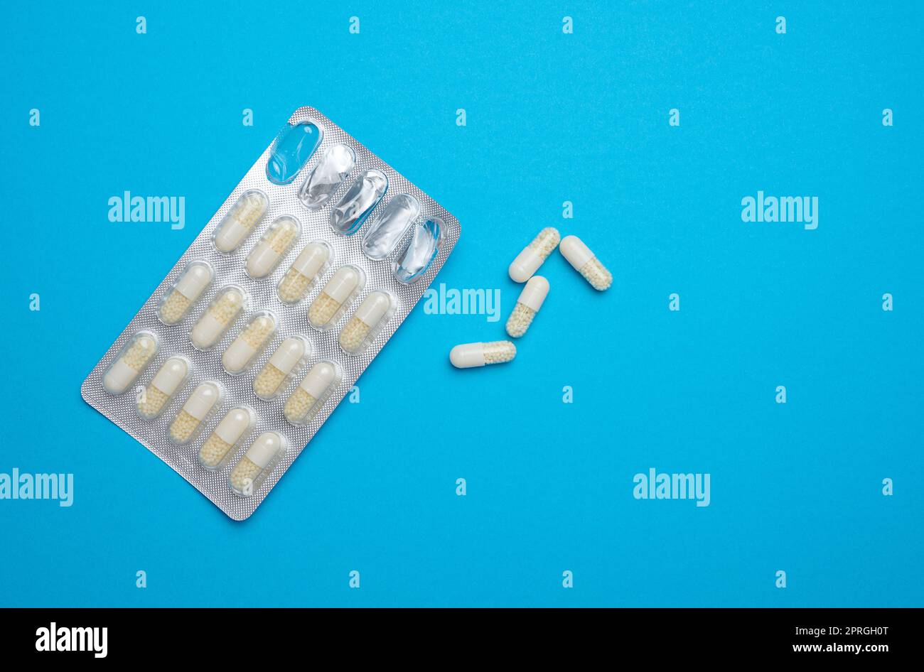 White oval pills and blister pack on a blue background Stock Photo