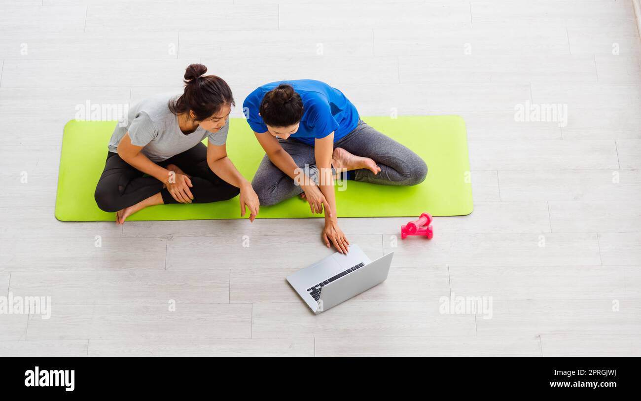 adult and young woman in sportswear sitting floor on mat with dumbbells ...