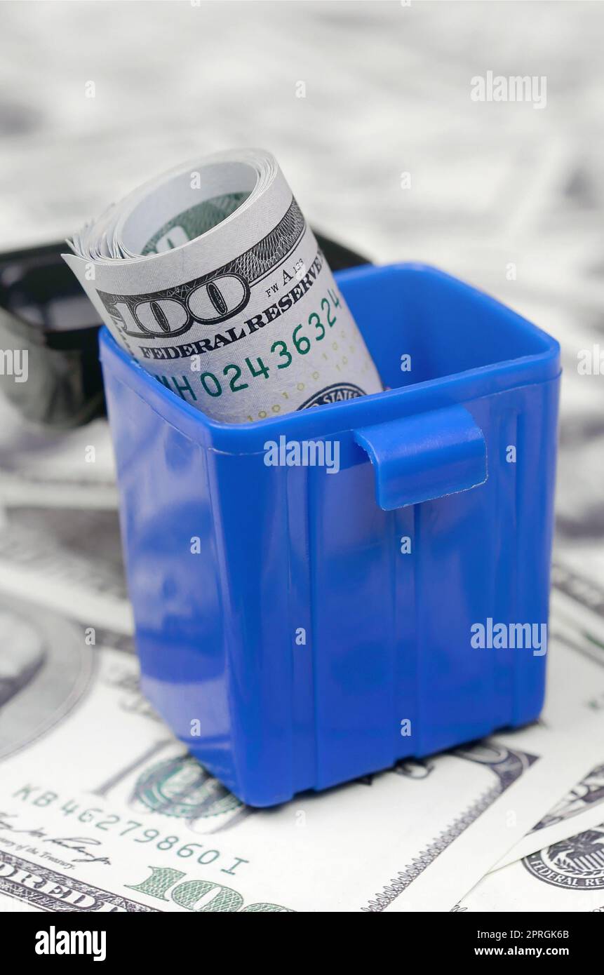 American cash notes are thrown into the trash bin on a multitude of hundred dollar bills. Financial abundance and oversupply. Senseless and reckless c Stock Photo