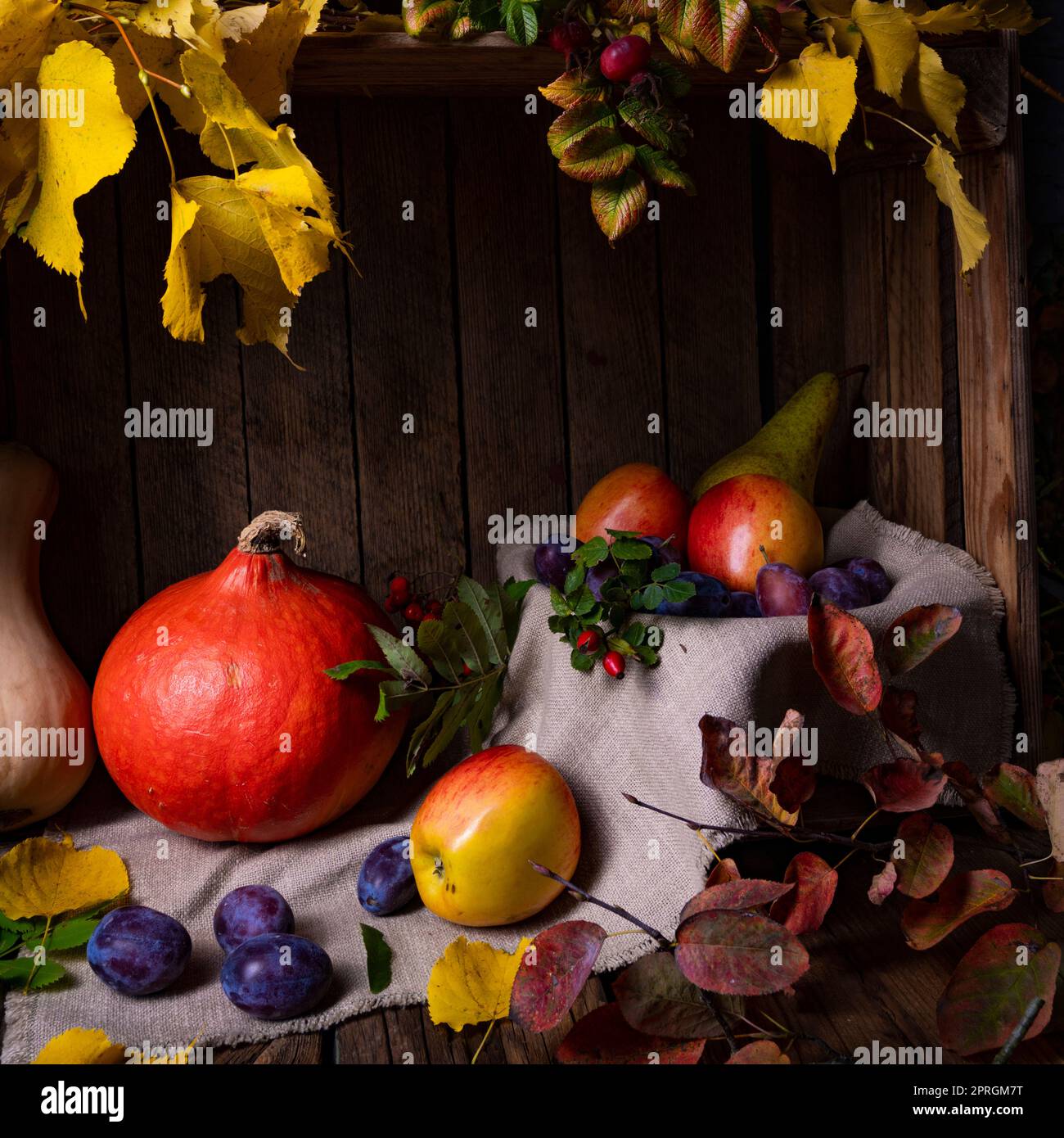 Various fruits in a wooden box with autumn leaves Stock Photo - Alamy