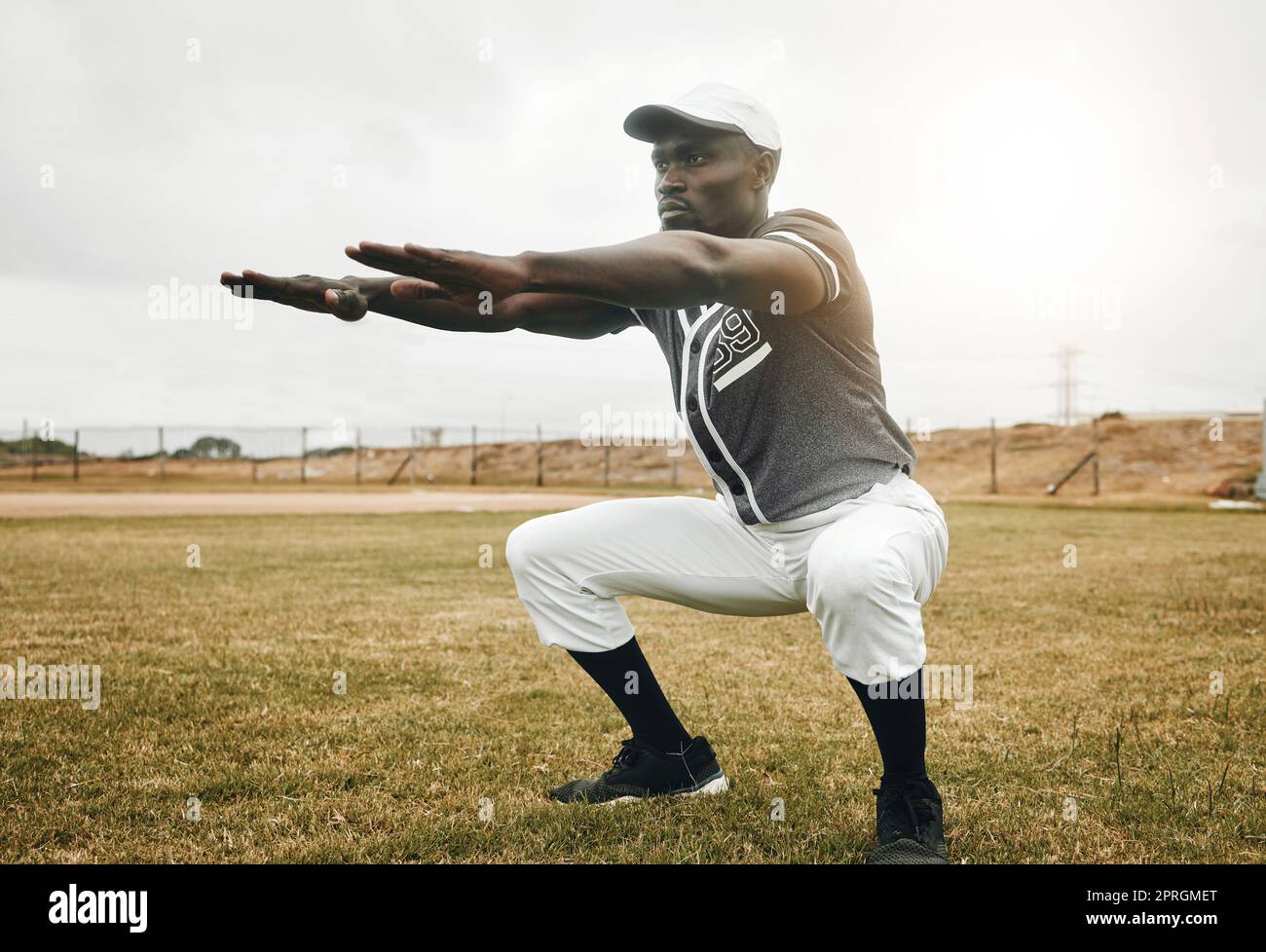 Baseball player, stretching and black man on sports field doing warm up exercise, workout practice for match. African male athlete outdoor with tshirt Stock Photo