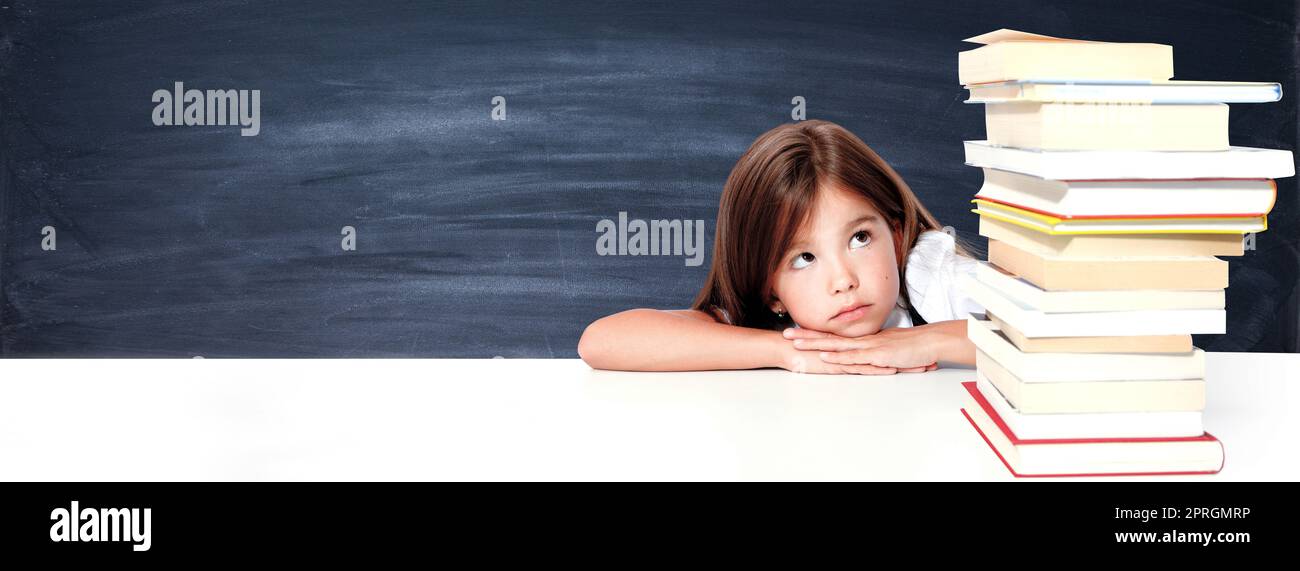 Young cute girl sitting at the table and reading a book Stock Photo - Alamy