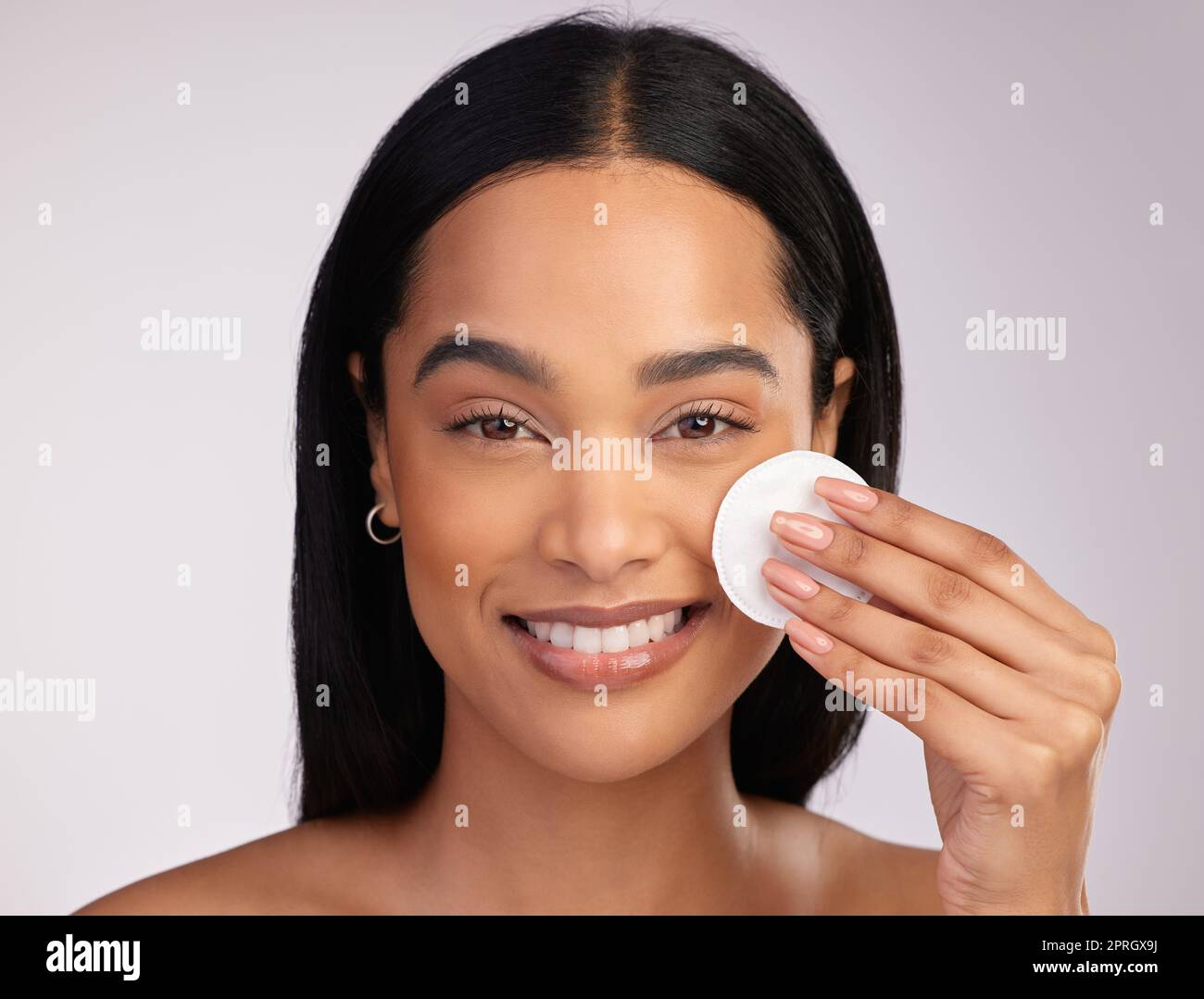 No clogged pores here. Cropped portrait of an attractive young woman exfoliating her face against a pink background Stock Photo