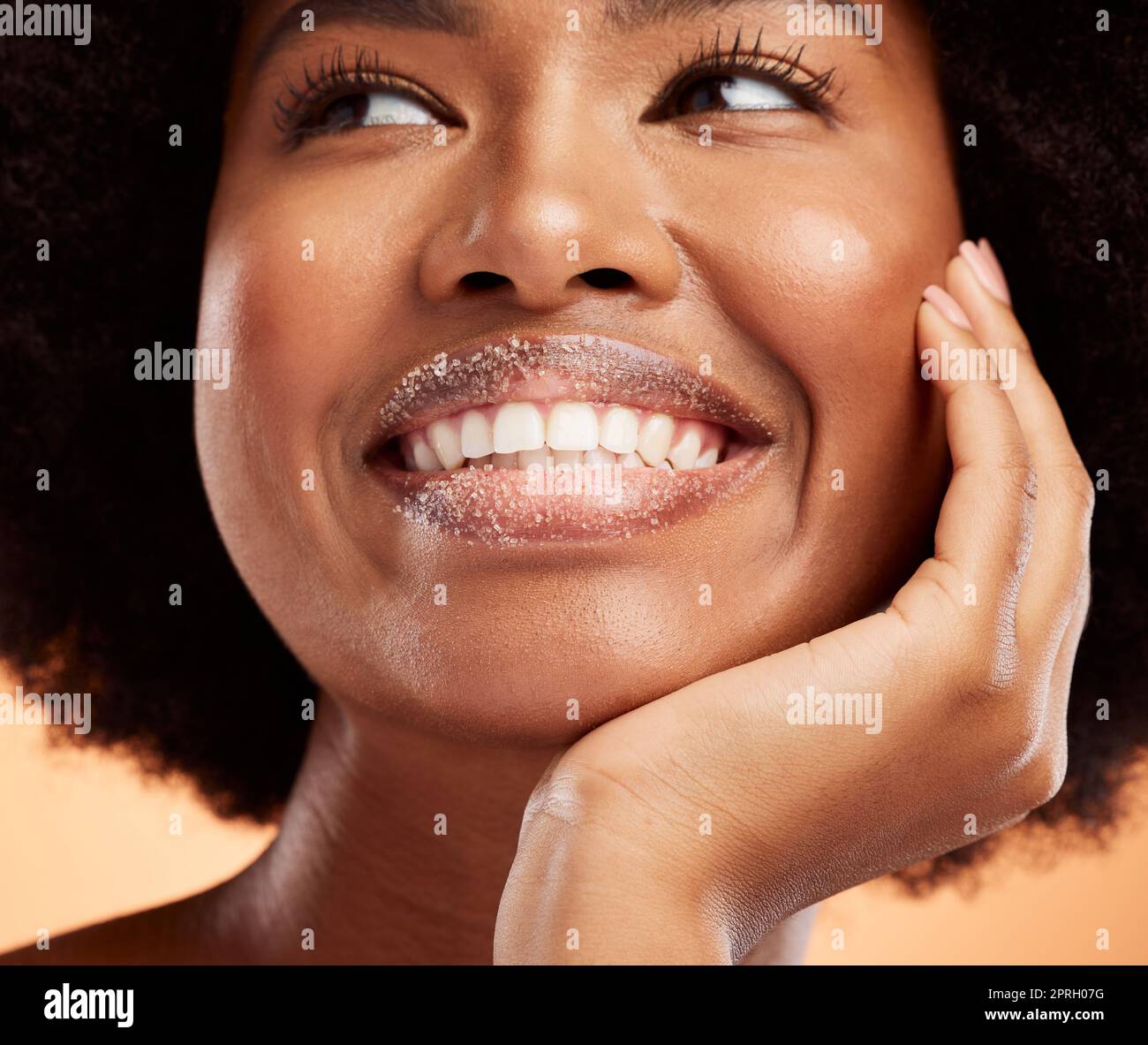 Black woman, lip sugar makeup or skincare health of exfoliate model with smile on orange studio background. Natural healthy, smooth skin and happy wit Stock Photo