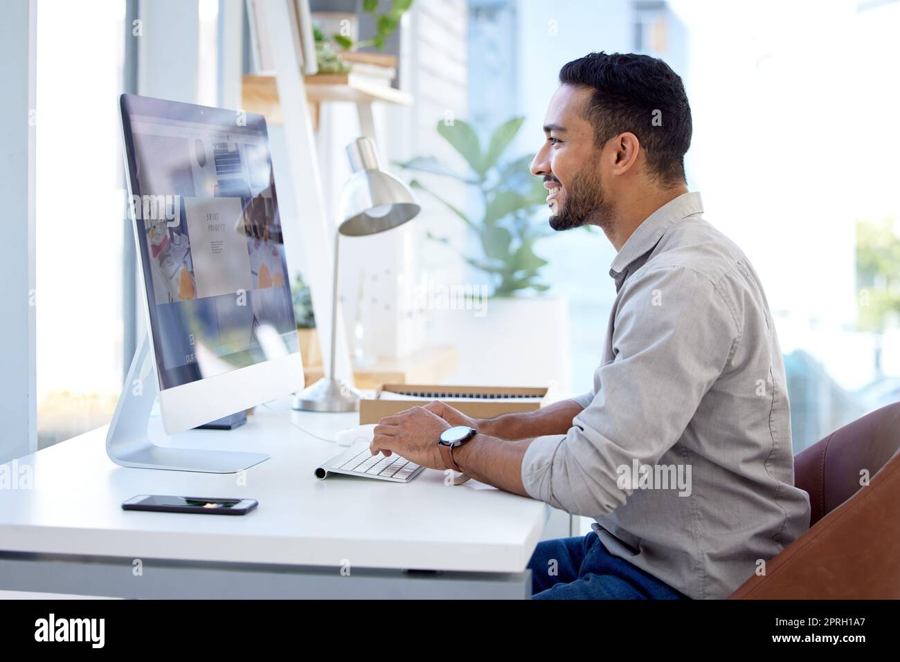 Young man sitting at desk in office and working on computer. Stock