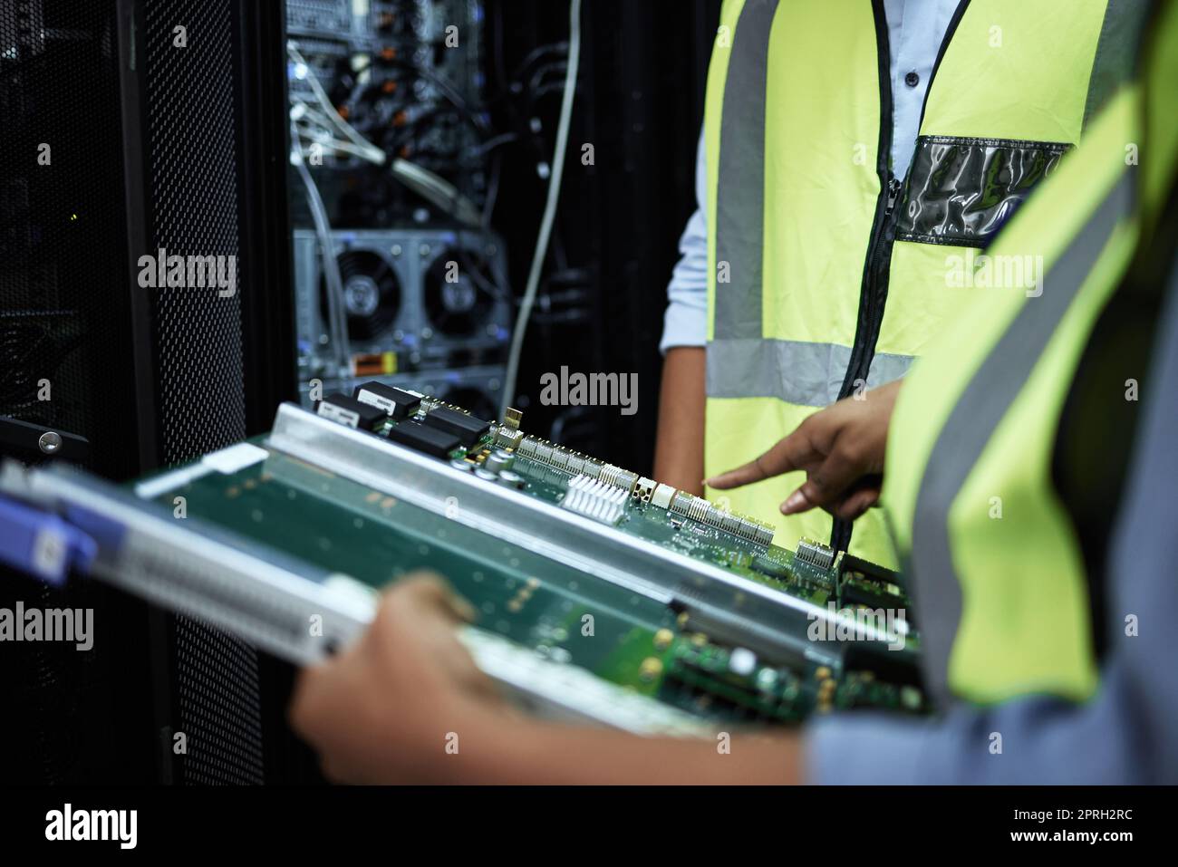 Taking a look at the hardware. two unrecognizable computer programmers working in a server room