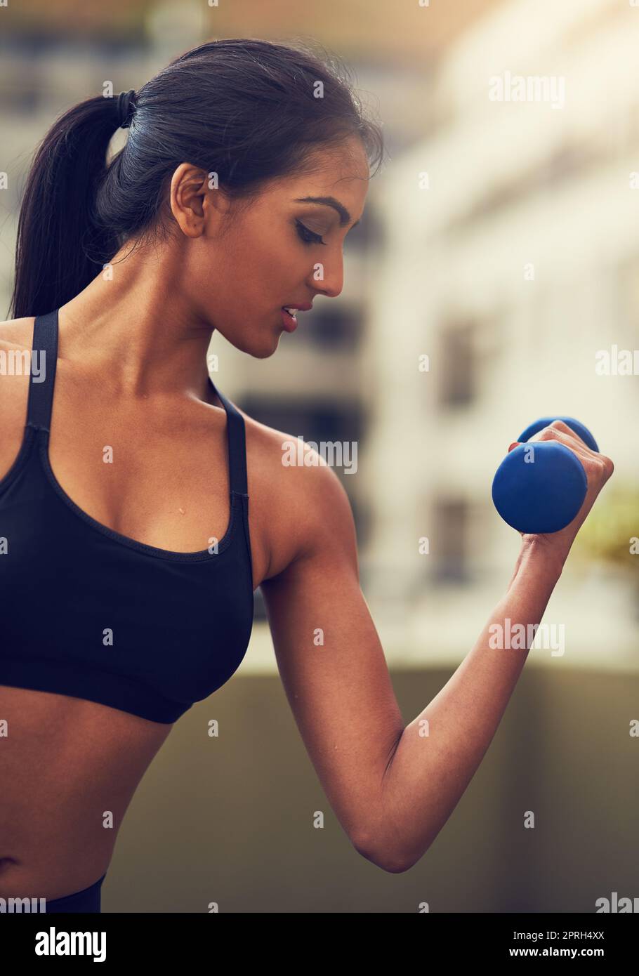 You are only as strong as you think you are. a young woman working out with dumbbells. Stock Photo