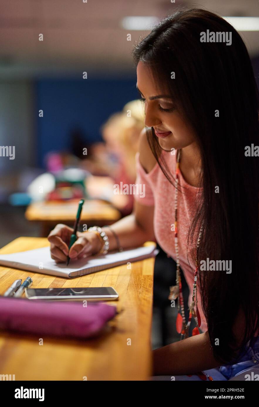 Shes a diligent student. a beautiful university student making notes while sitting in a lecture hall. Stock Photo