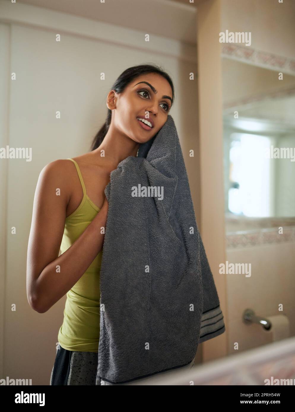 Brightening and energising her skin through her daily routine. a young woman drying her face with a towel in the bathroom. Stock Photo