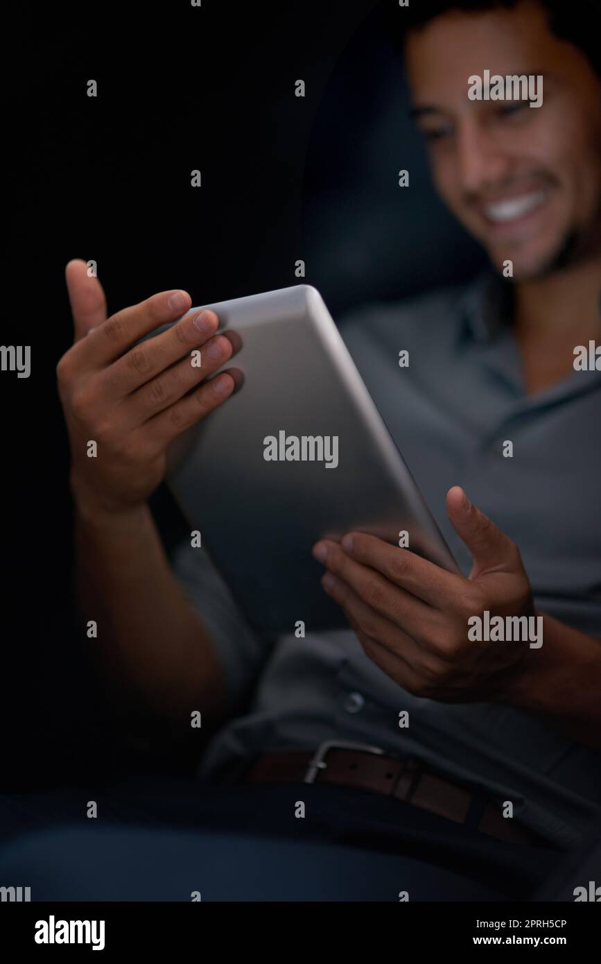 Its so simple to share and store information as needed. a young man using his tablet at night. Stock Photo