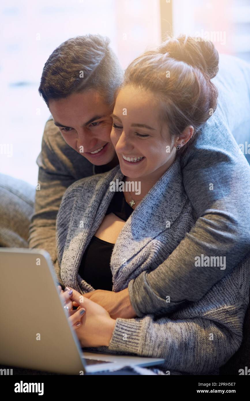 Lemme see that. an affectionate young couple surfing the net while relaxing on the sofa at home. Stock Photo