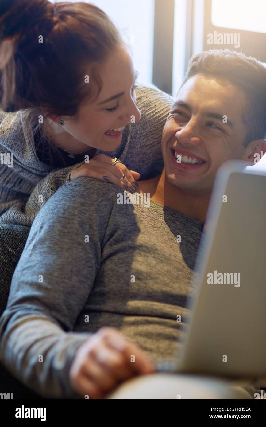 Thats amazing. an affectionate young couple surfing the net while relaxing on the sofa at home. Stock Photo