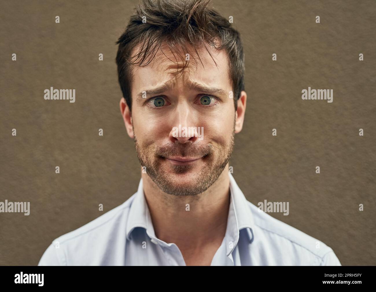 Hes a real standout. Portrait of a young man pulling a funny face against a dark background. Stock Photo