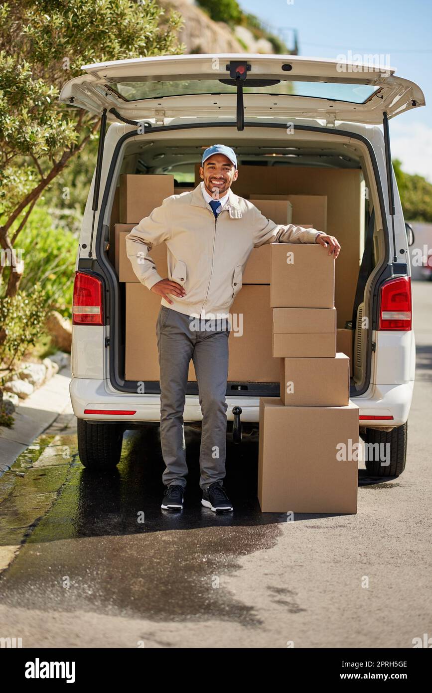 Whatever you are, be a good one. Portrait of a friendly delivery man unloading cardboard boxes from his van. Stock Photo