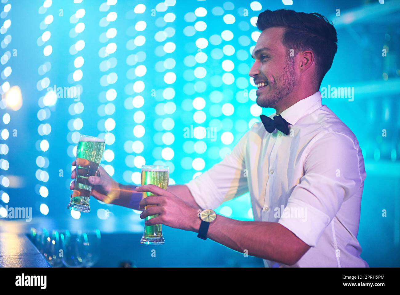 First class bartending. a happy bartender serving two glasses of beer at a bar. Stock Photo