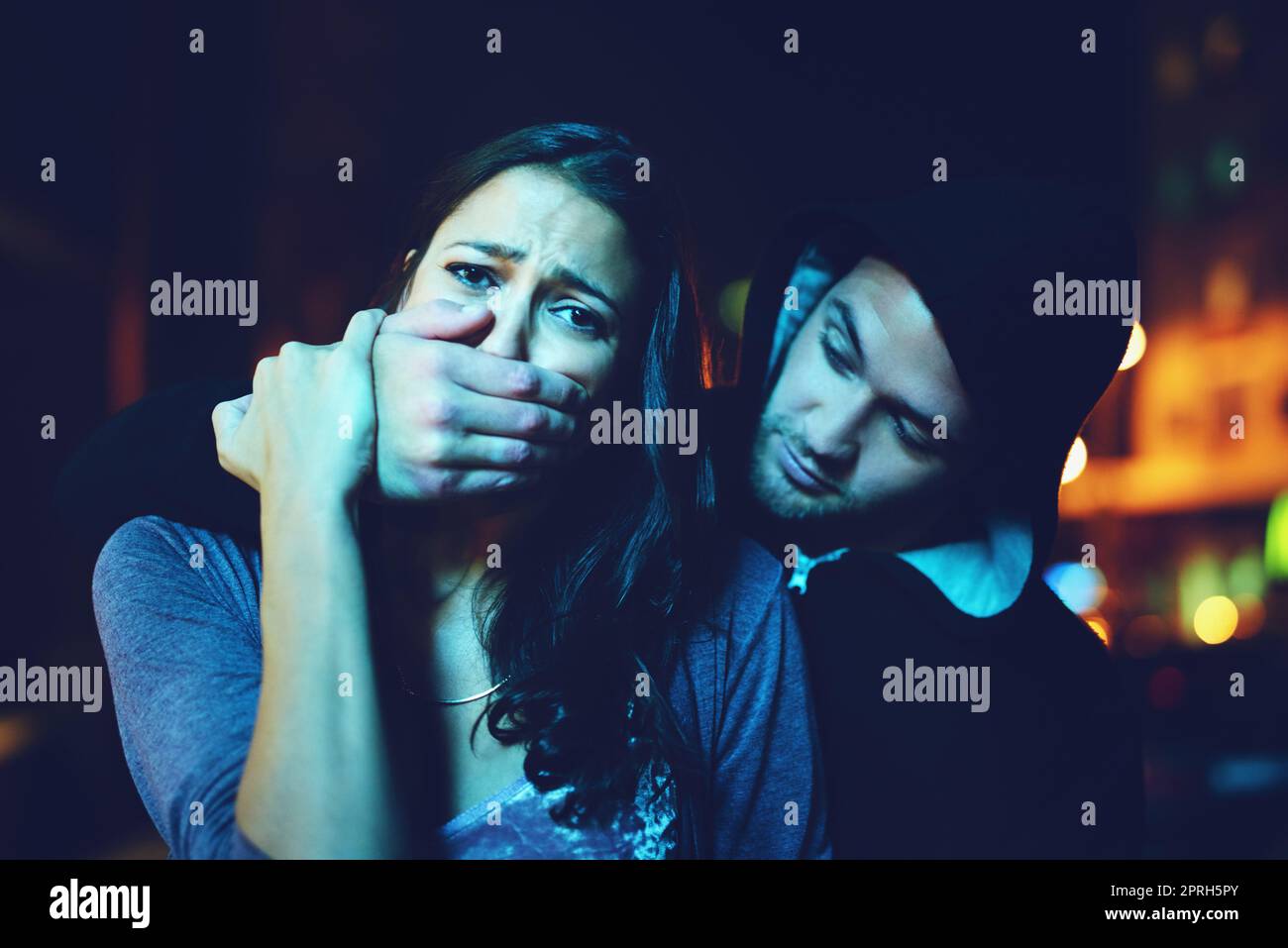 Now she truly knows crime. Portrait of a frightened young woman with her assailants hand over her mouth. Stock Photo