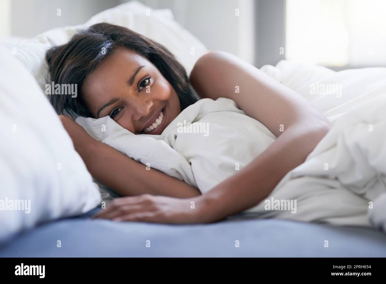 Saturday is my duvet day. a happy young woman waking up in her bed at home. Stock Photo