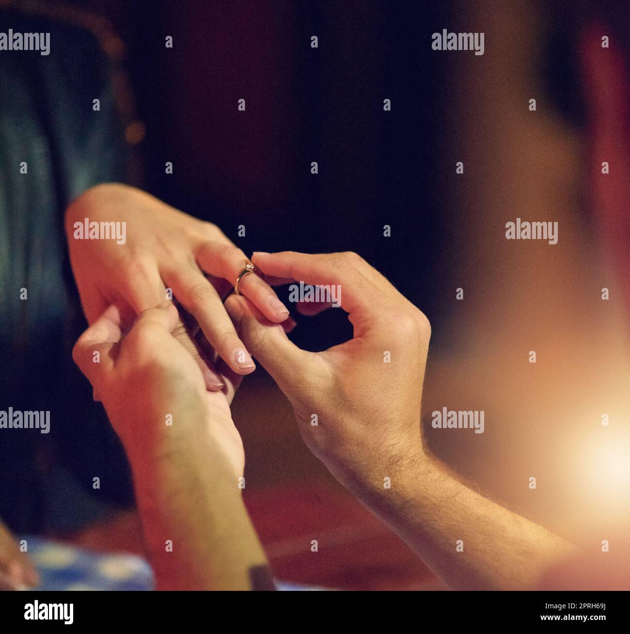 This ring is a symbol of my love and commitment. a man putting an engagement ring onto his fiancees finger. Stock Photo