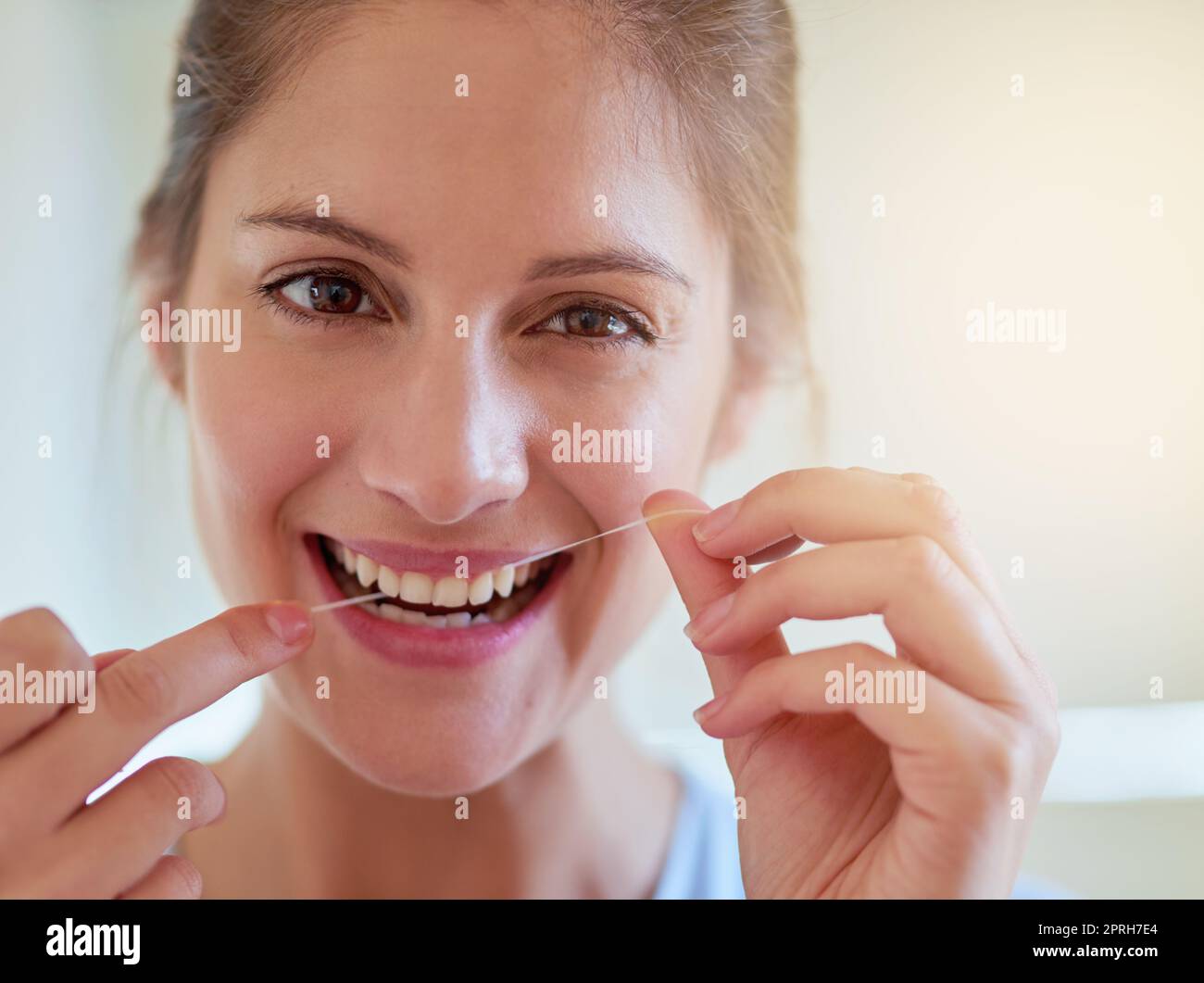 Make it a habit. Portrait of a young woman flossing her teeth in a bathroom. Stock Photo
