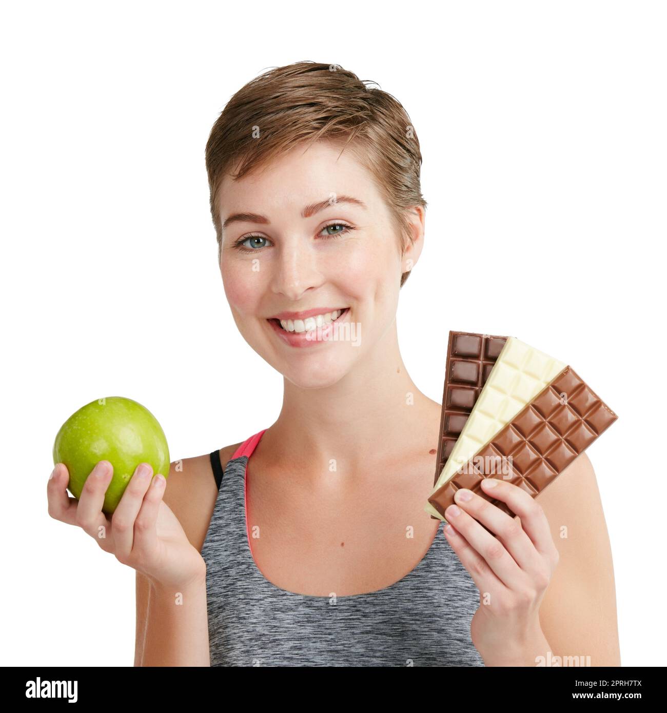 You always have a choice. Studio portrait of a fit young woman deciding whether to eat chocolate or an apple against a white background. Stock Photo