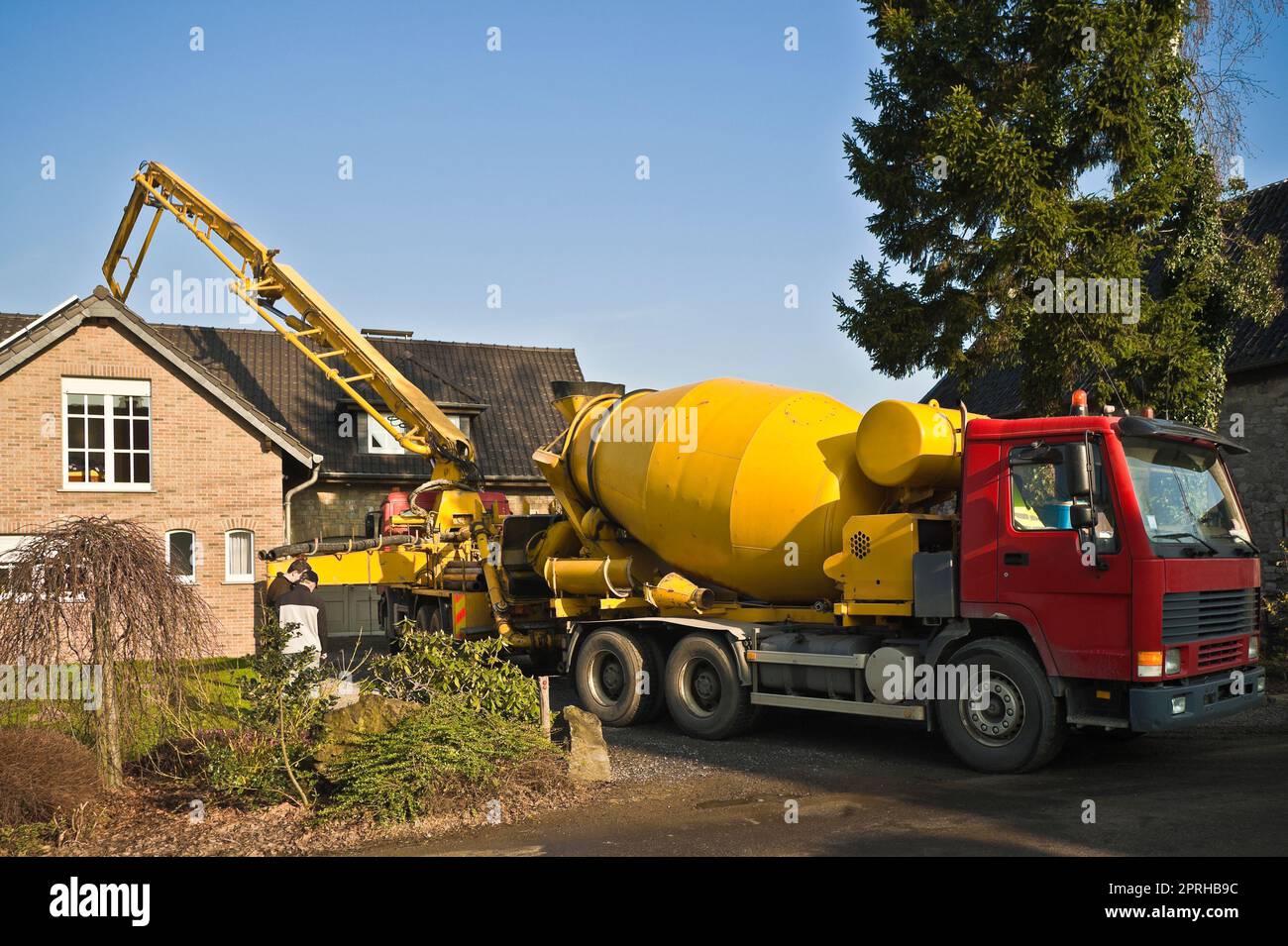 Truck-mounted concrete pump pumping concrete behind a single-family house Stock Photo
