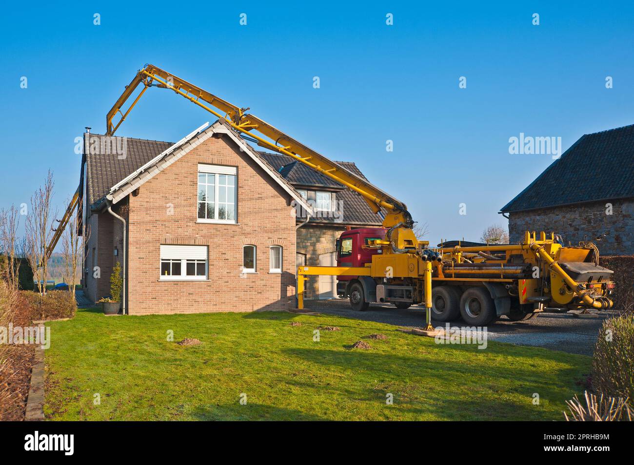 Truck-mounted concrete pump pumping concrete behind a single-family house Stock Photo