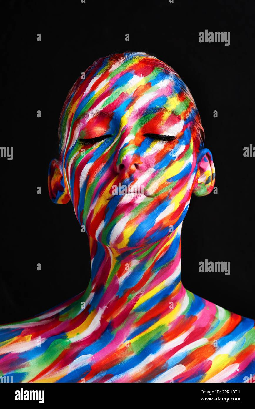 young black woman with fluorescent prints on skin, cosmic paint glowing on  neon lights, black background in studio. female with body art closing half  of face, touching. beauty, fashion concept Stock Photo