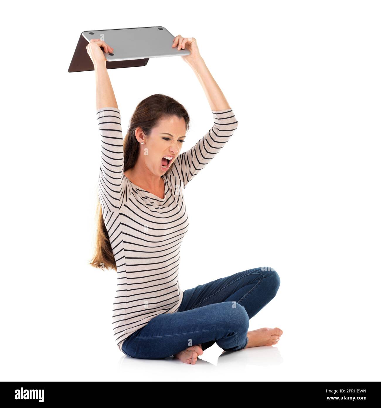 Im so frustrated with this. Studio shot of a young woman using a laptop against a white background. Stock Photo