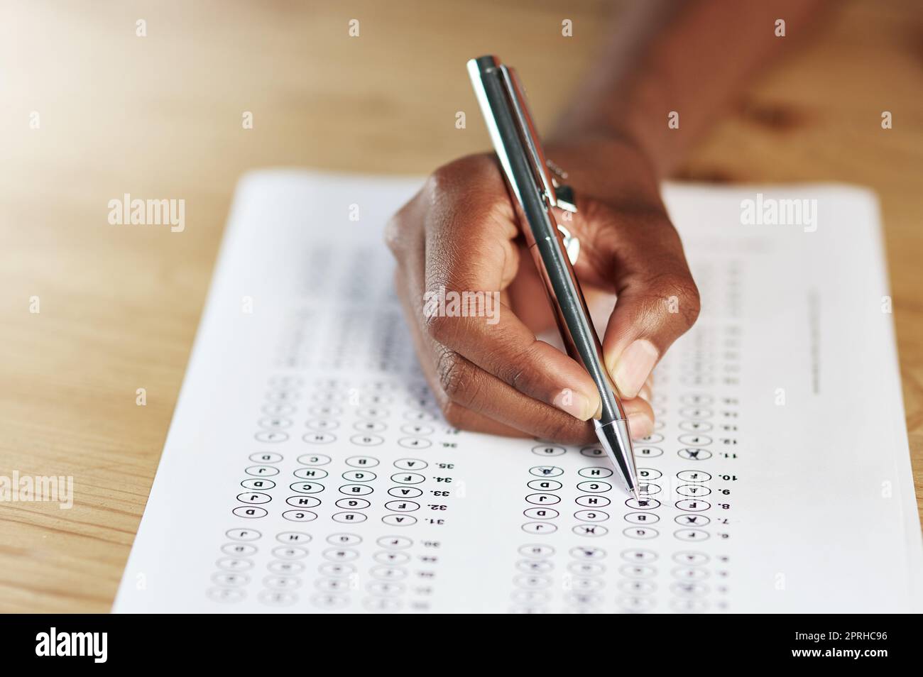 Those hours of studying will pay off. a person filling in an answer sheet for a test. Stock Photo