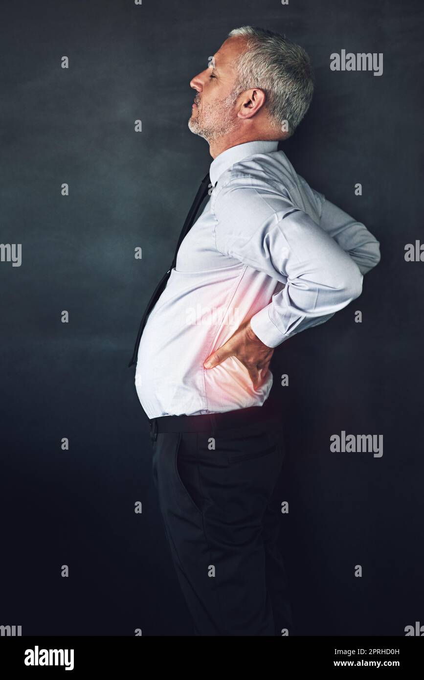 Bad posture habits are coming back to haunt him. Studio shot of a mature man experiencing muscular strain. Stock Photo