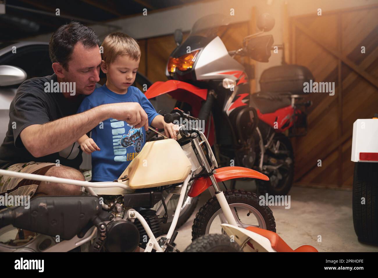 Dad is his best friend. a father and son fixing a bike in a garage. Stock Photo