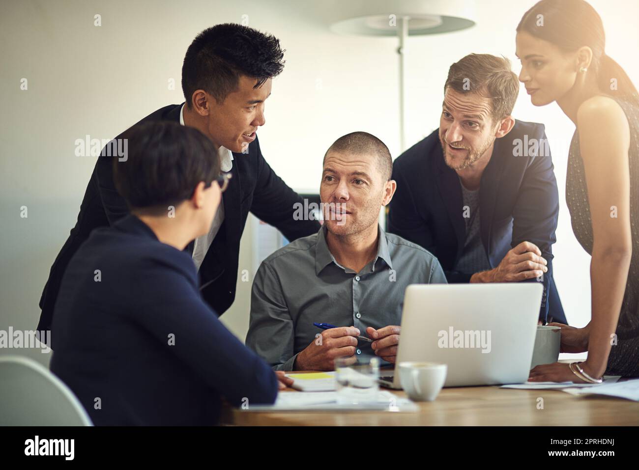 Assigning his team members according to their specialization. a group of coworkers discussing something on a laptop during a meeting. Stock Photo