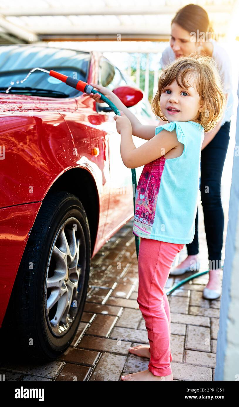 Who doesnt like to platy with water. a mother and daughter washing a car together. Stock Photo