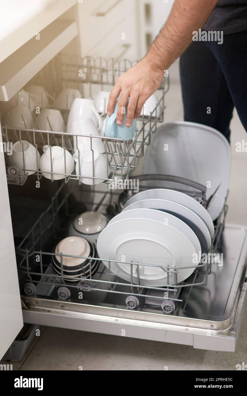 Keeping your dishes clean. a person loading a dishwasher at home Stock