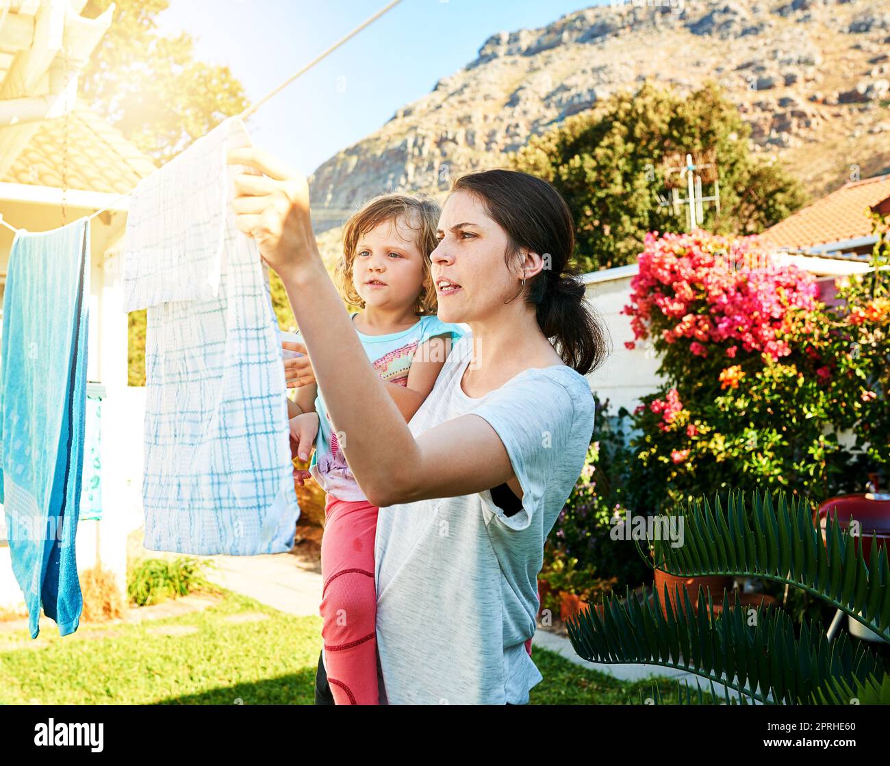 Getting to know moms job. a mother and daughter hanging up laundry together outside. Stock Photo