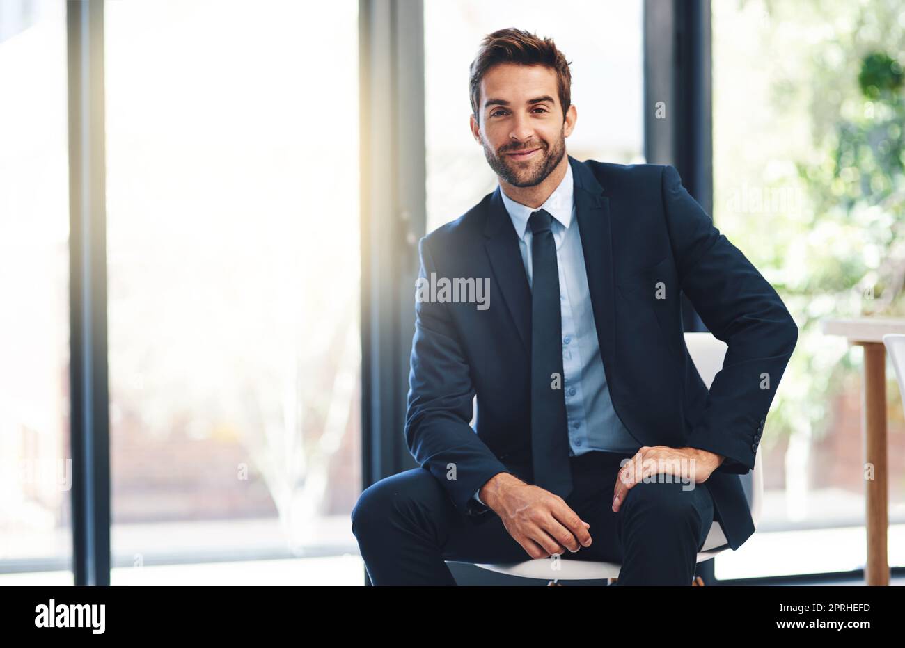 Premium professionalism. a handsome young businessman sitting on a chair in a modern office. Stock Photo