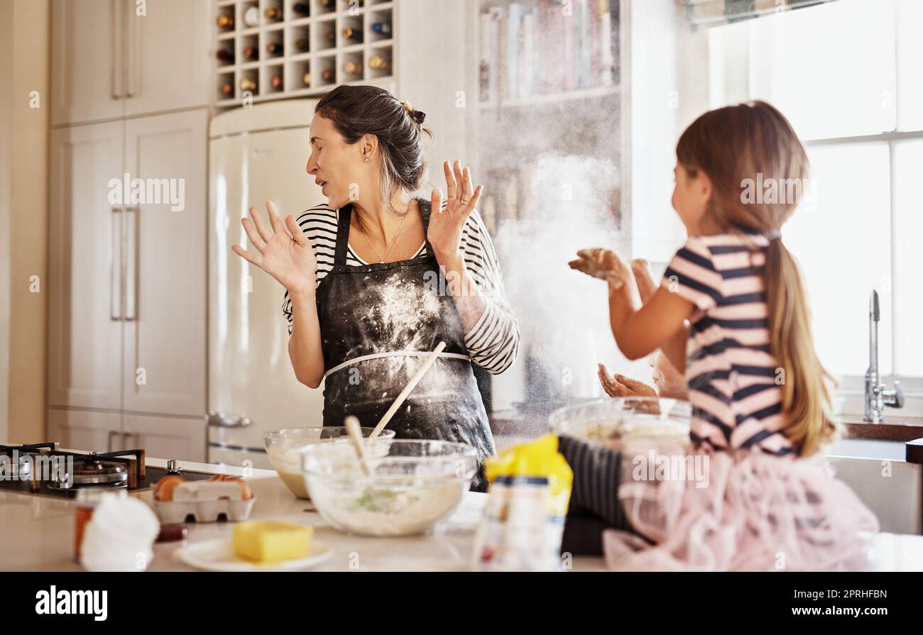 Getting messy is part of the fun of baking together. two little girls having fun while baking with their mother in the kitchen. Stock Photo