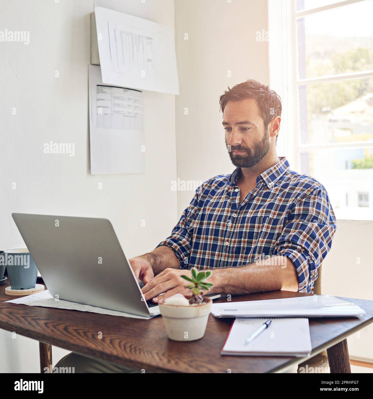 Getting down to business. a man sitting at a desk working on a laptop. Stock Photo