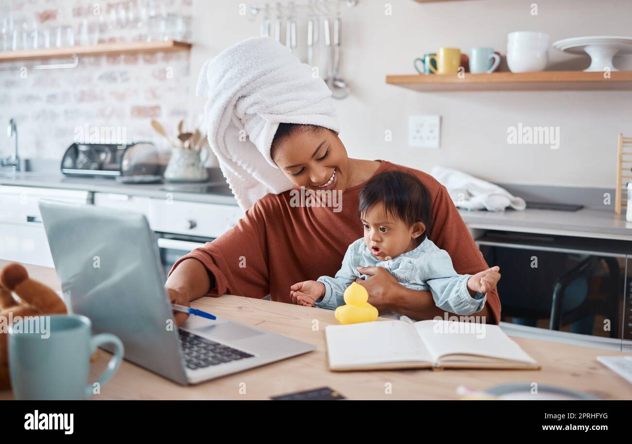 Down syndrome, baby and laptop with mother working in a kitchen